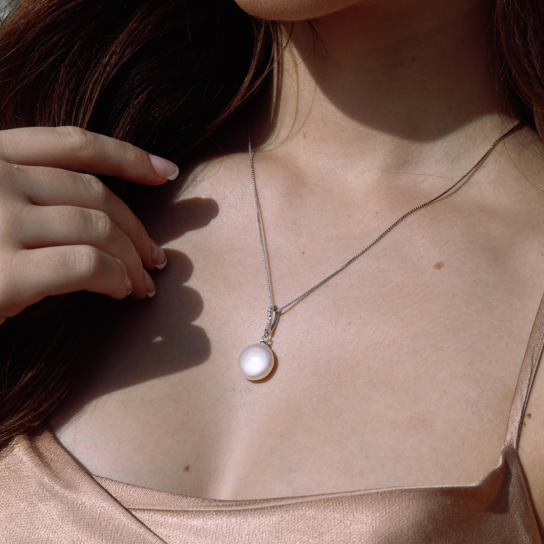 Presenting our Clarissa Pendant, an enchanting blend of sophistication and contemporary allure. Crafted from sterling silver, this pendant boasts sparkling cubic zirconias, complemented by a striking sizable coin-shaped freshwater pearl suspended below, adding an exquisite touch to any ensemble. Pair it with the Clarissa Earrings to curate a truly breathtaking combination.