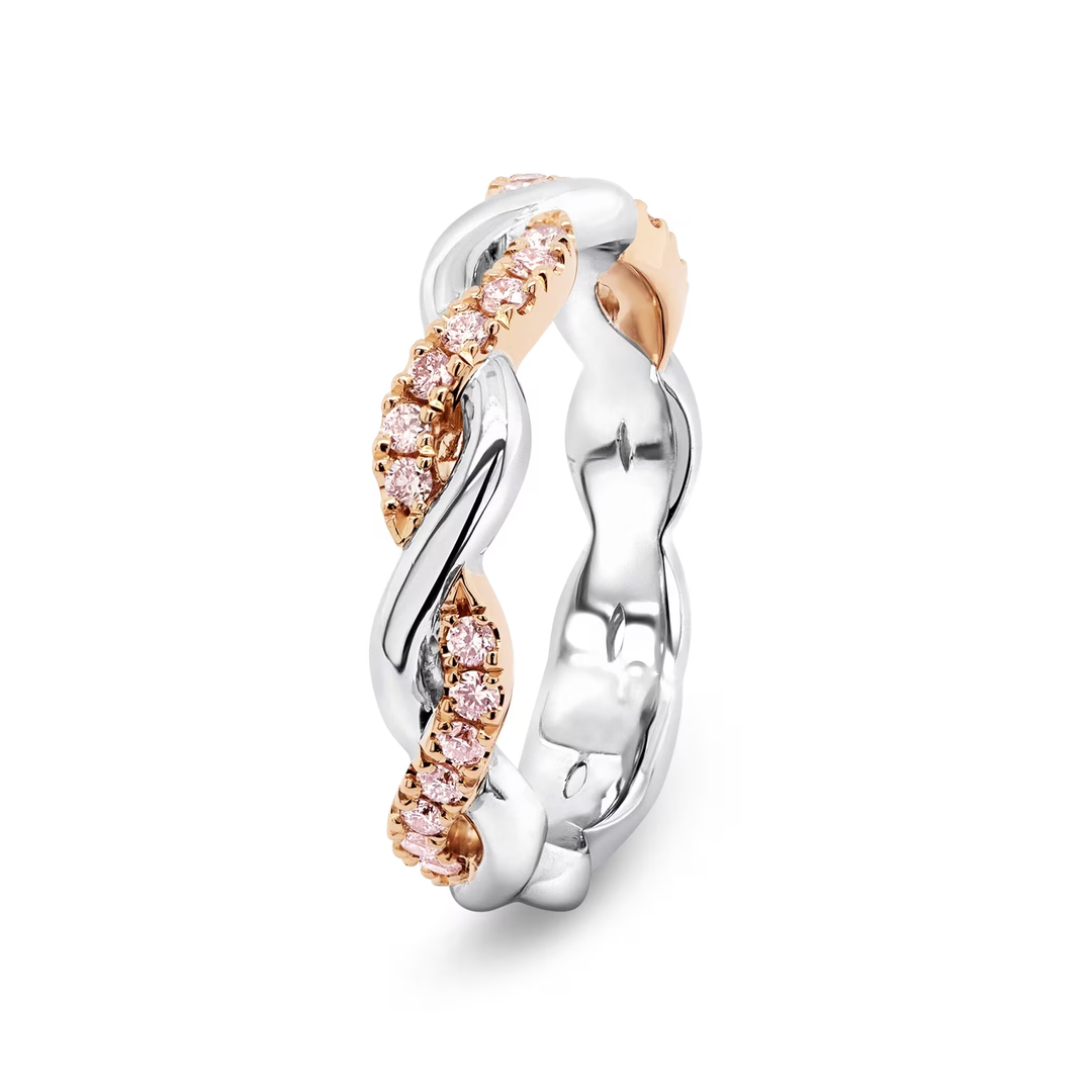 A twisted two-tone ring featuring polished silver and rose gold metal with rows of small round pink gemstones, shown on a clean white background.