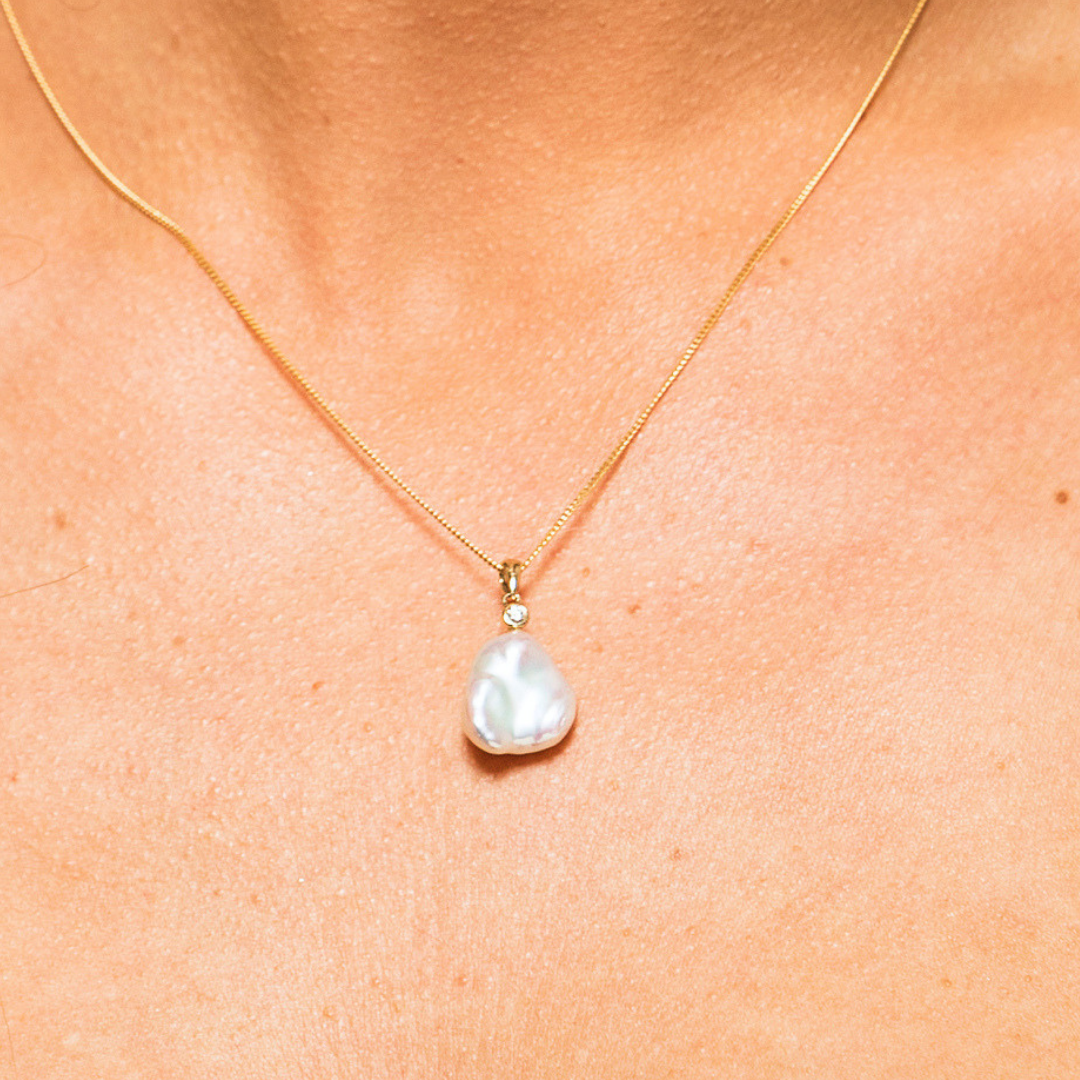 The Elsie Pendant captures elegance in every unique curve. Showcasing the natural beauty of an organic Keshi pearl and accented by a brilliant diamond stud, this pendant embodies refined sophistication. Perfectly suited for any occasion—whether formal, casual, or bridal—it’s a stunning piece that makes a lasting impression.