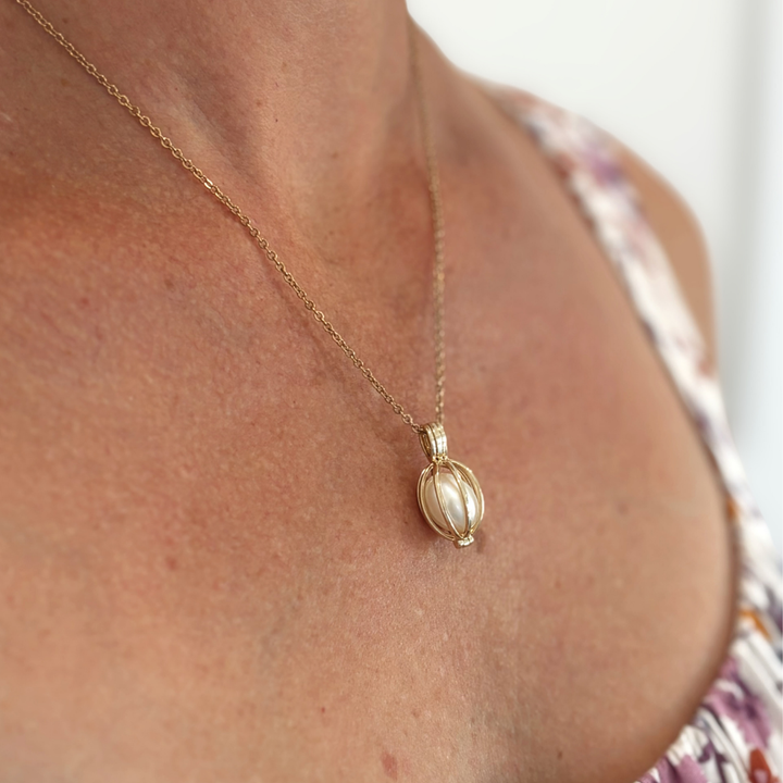 Timeless and sophisticated, the Celia Pendant features an openable 9ct yellow gold cage designed to showcase a white Freshwater pearl. The polished structure frames the pearl beautifully, allowing its natural lustre to shine from every angle.

Its hinged opening allows you to easily interchange the pearl, offering versatility for every occasion. A delicate and refined piece for lovers of classic pearl jewellery.